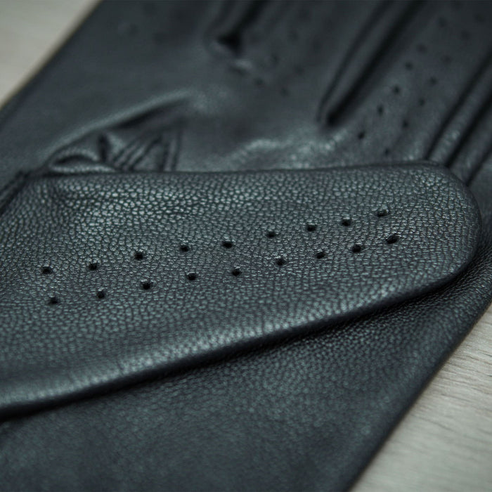 Detailed close-up of Leatherick men's black genuine leather driving gloves highlighting the soft grain texture and breathable pin-hole perforations.