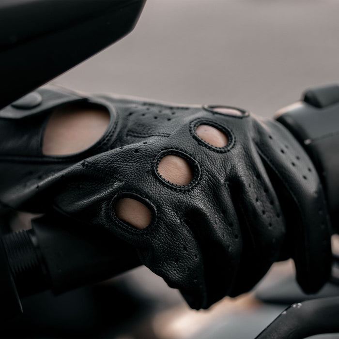 Leatherick men's black real leather driving gloves with knuckle holes worn while gripping motorcycle handlebars.