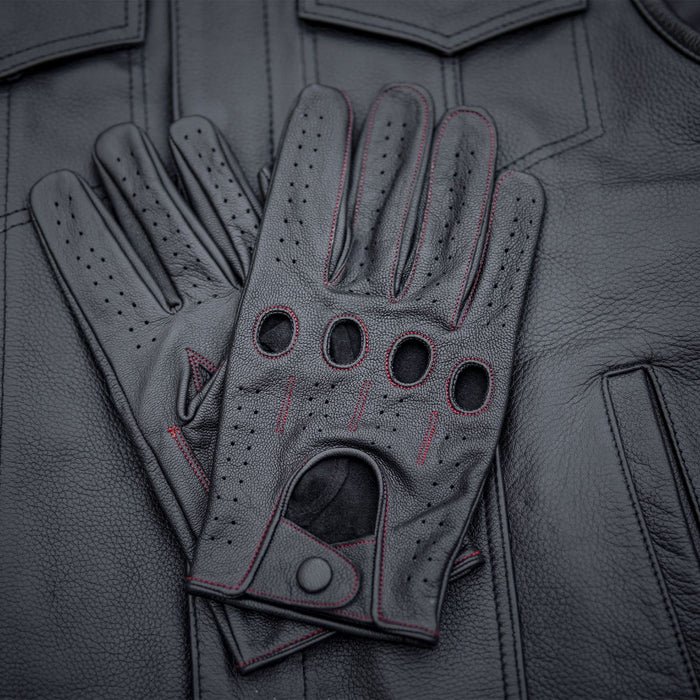 Leatherick men's black genuine leather driving gloves with red stitching and knuckle holes resting on a black leather jacket.