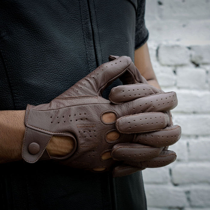 Leatherick men's dark brown genuine leather driving gloves with knuckle holes worn with a matching black leather vest.