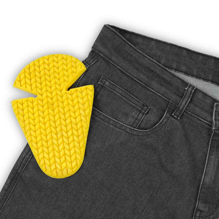 A close-up view of the waistband and front pocket of men's black single-layer motorcycle riding jeans next to a yellow protective hip armor insert.